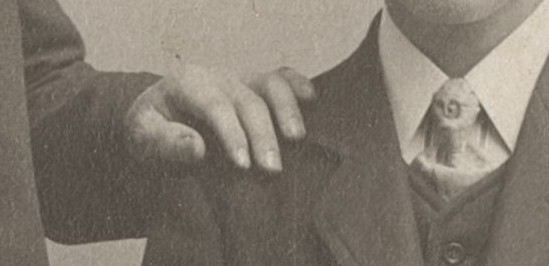 Lähikuva mustavalkoisesta kuvasta, jossa miehen käsi on toisen miehen olkapäällä