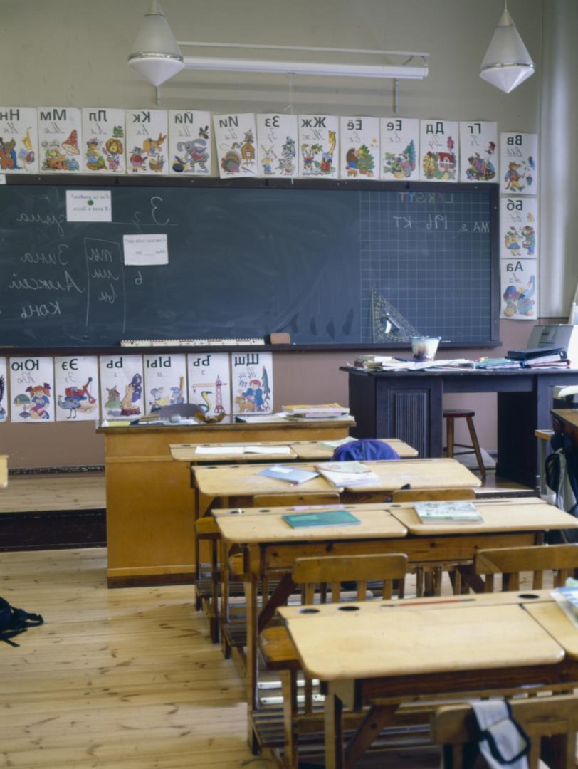 Luokkahuone, pulpettirivien takana näkyy liitutaulu.