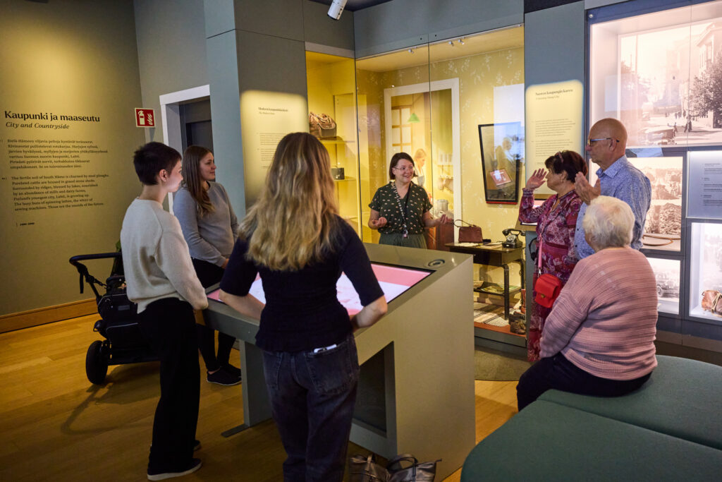 Väkijoukko kuuntelee opastusta näyttelyssä.